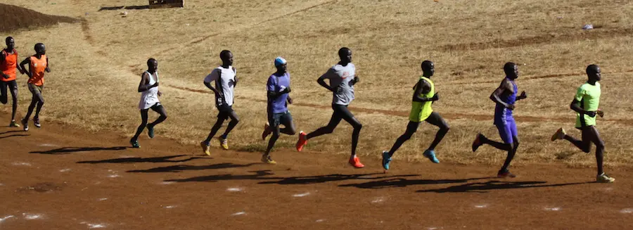 A group of men running on dirt ground.