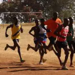 A group of men running on dirt ground.