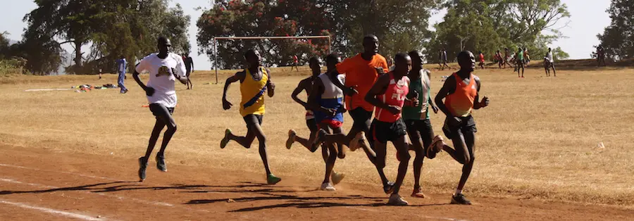A group of men running on dirt ground.