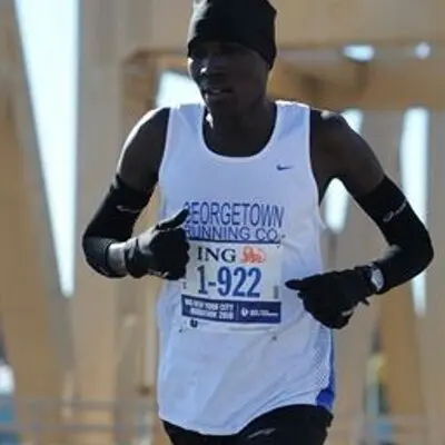 A man running in the marathon wearing gloves and a hat.