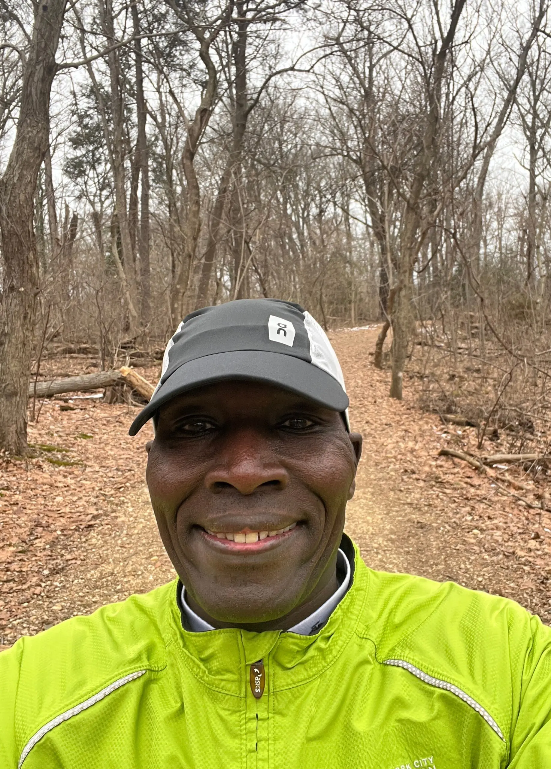 A man in yellow jacket standing on dirt road.