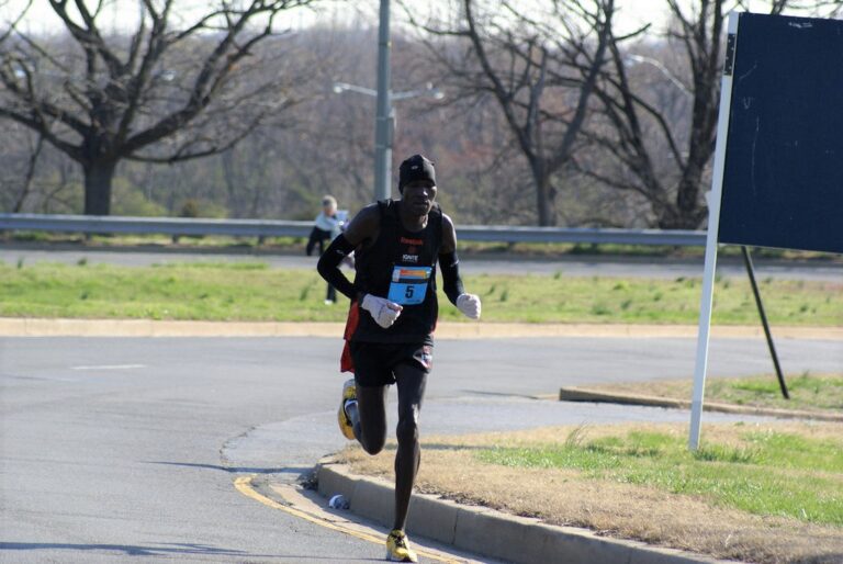 A man running in the street with a race number on his shirt.