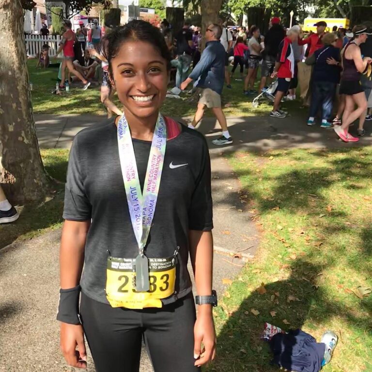 A woman standing in front of a crowd with her medal.