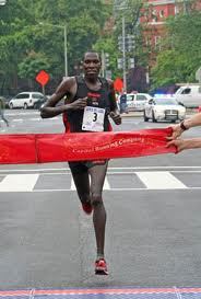 A man is running in the street while holding onto a red ribbon.