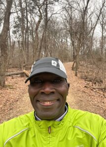 A man in yellow jacket standing on dirt road.